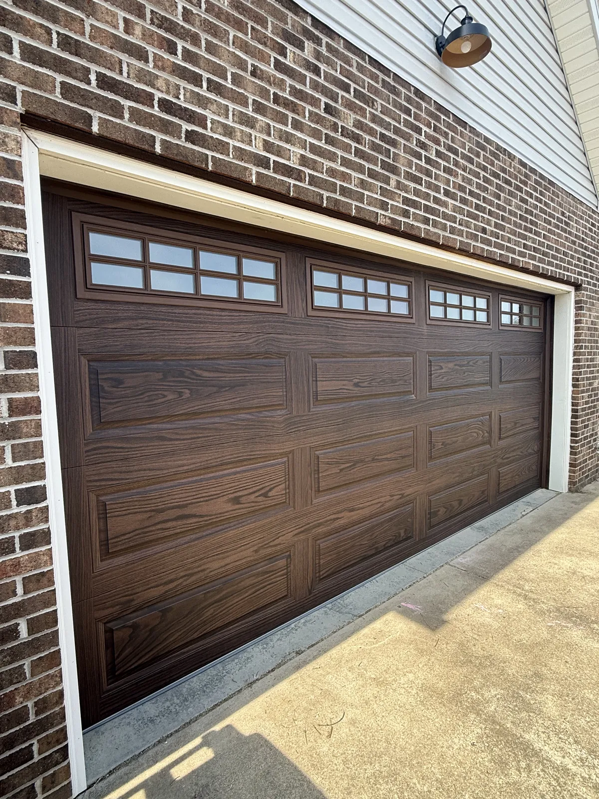 Warm Woodgrain on Brick garage after — A tired opening upgraded to warm woodgrain CHI doors that frame the brick.