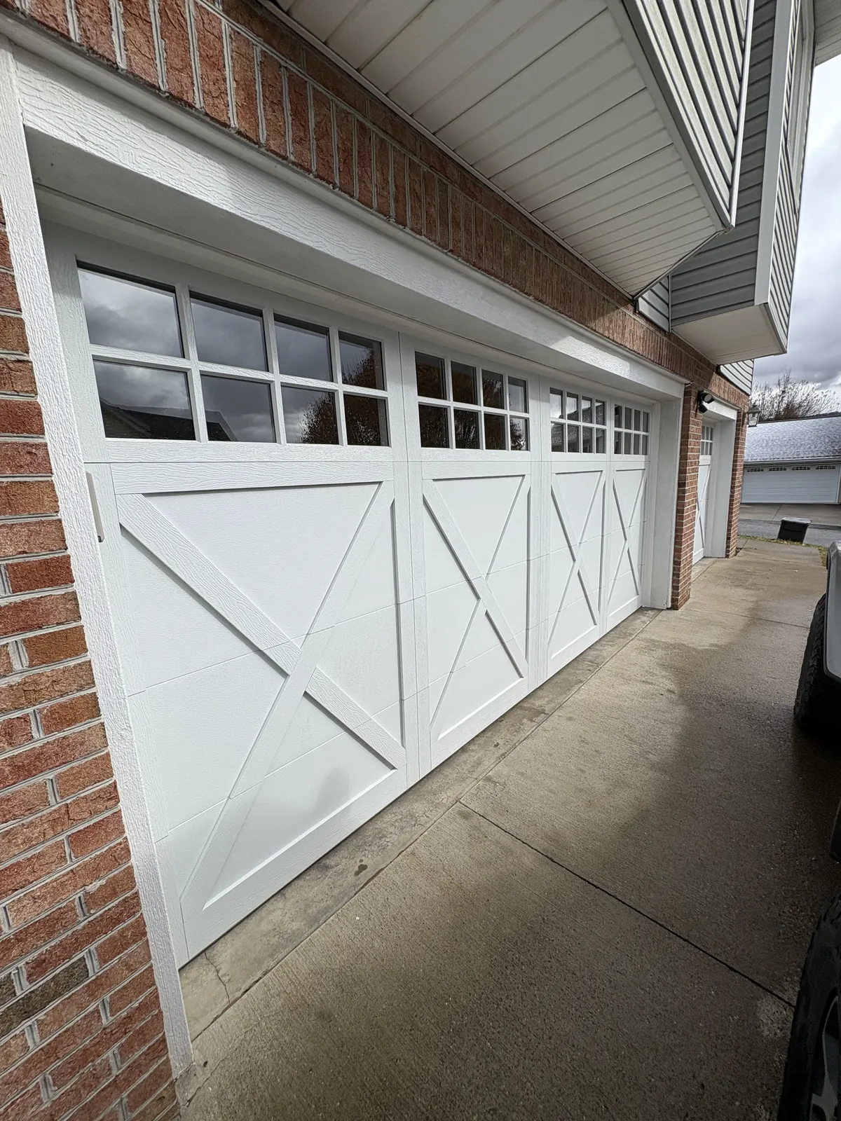 White carriage-style CHI doors on a brick home by Bear Door Services
