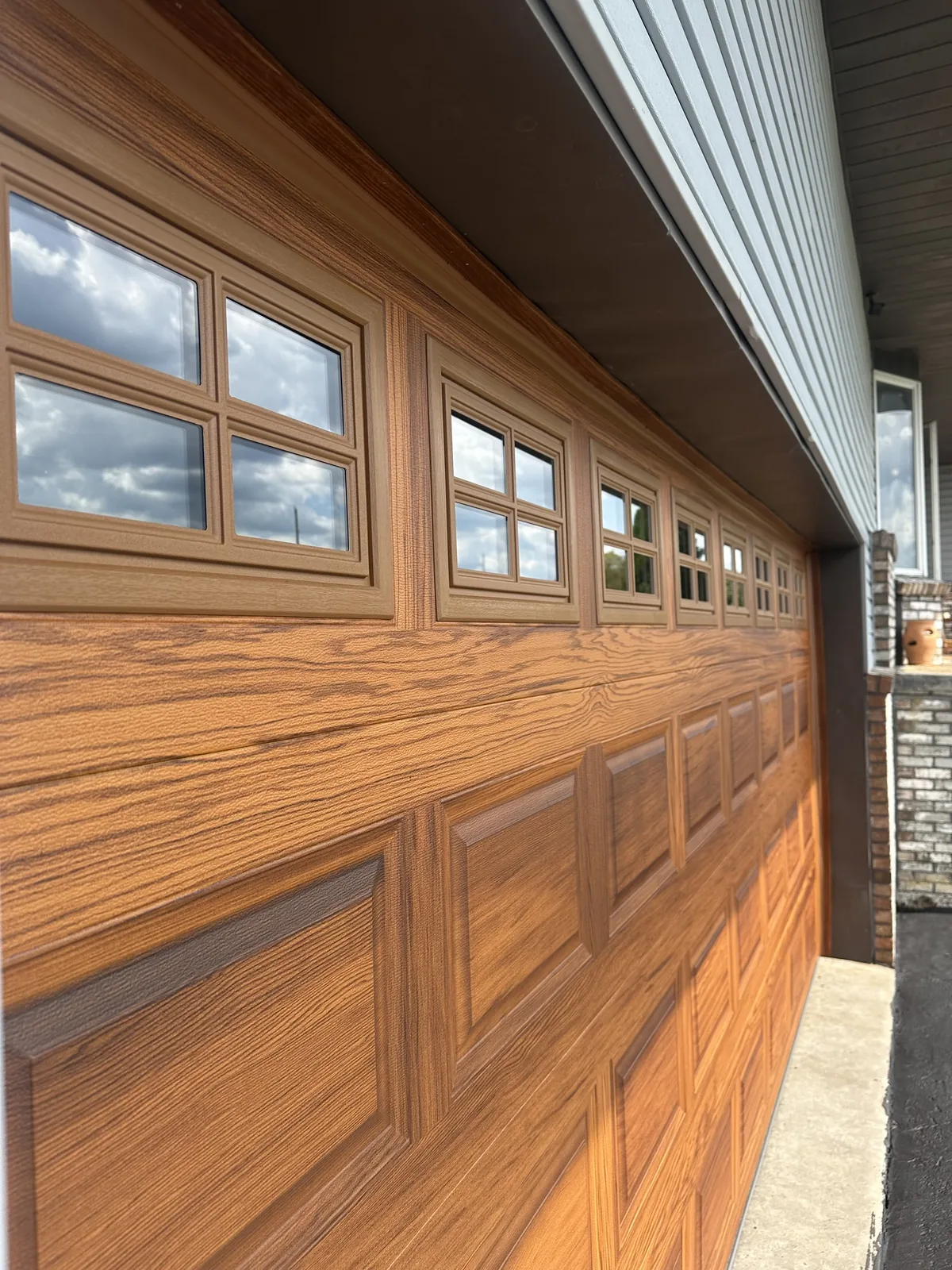 Woodgrain CHI on Brick garage after — A warm woodgrain CHI carriage door with colonial glass.