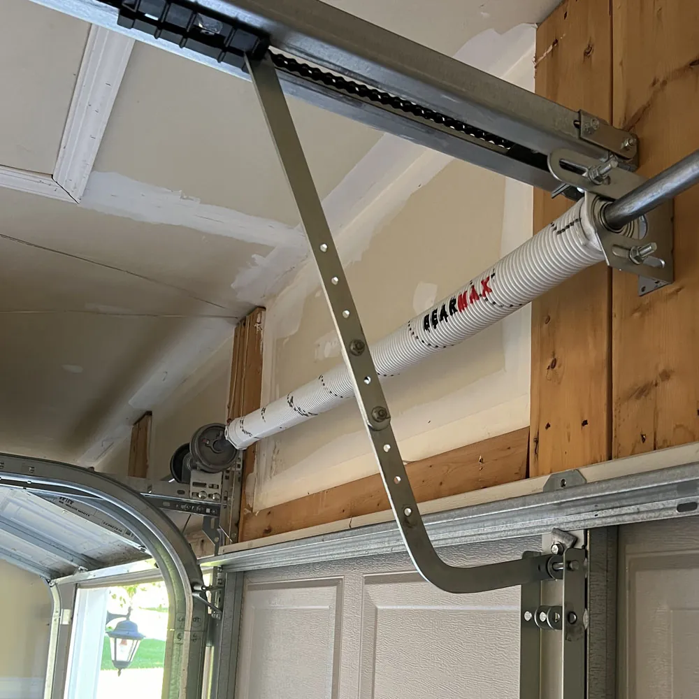 Newly installed white BEARMAX torsion spring above a garage door