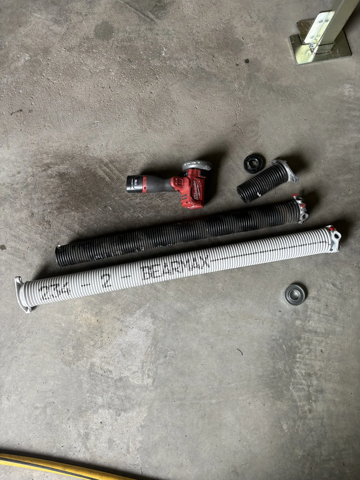 Broken galvanized spring next to a premium BEARMAX spring